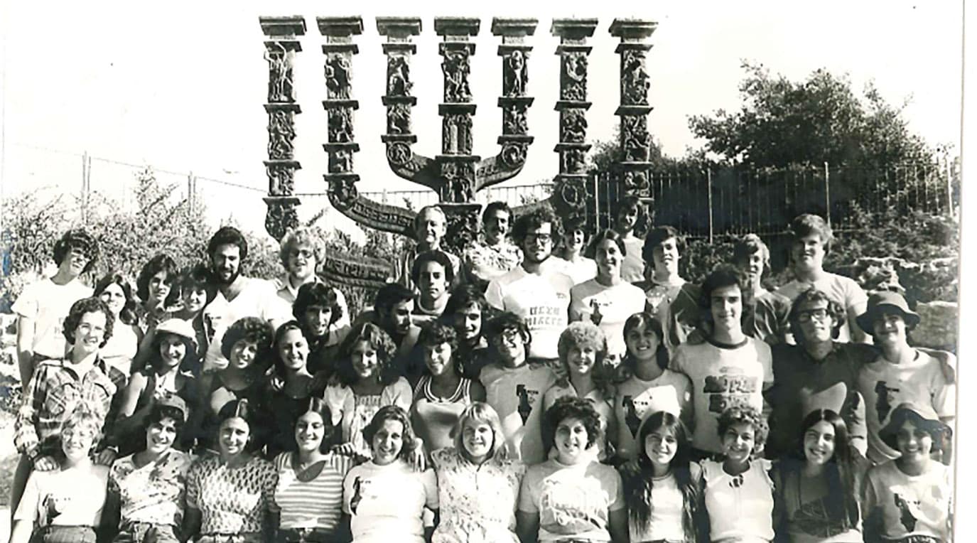 A diverse crowd of people celebrating at a concert, raising their hands and cheering.